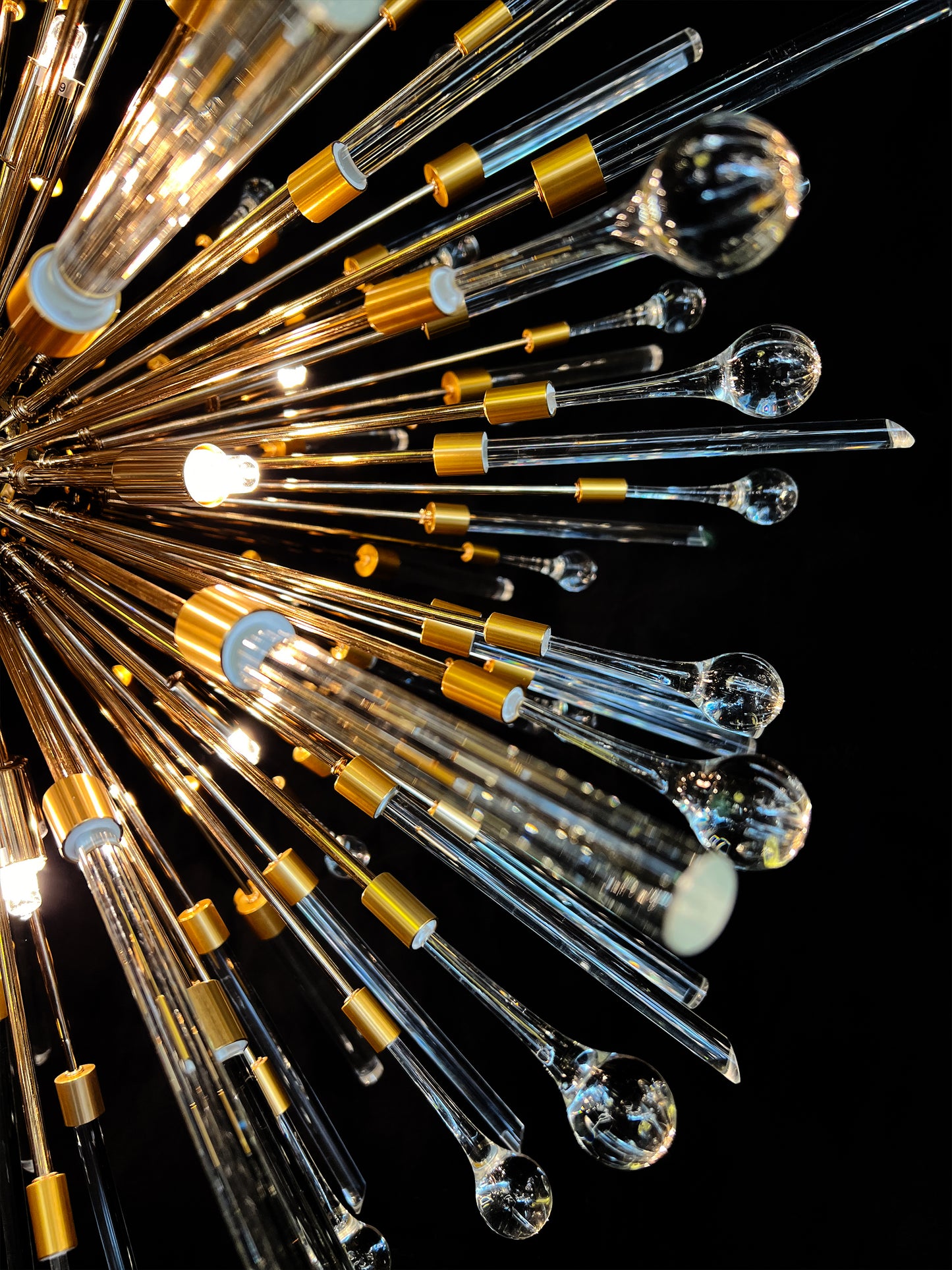 Modern pendant chandelier with gold frame and luminous glass rods.