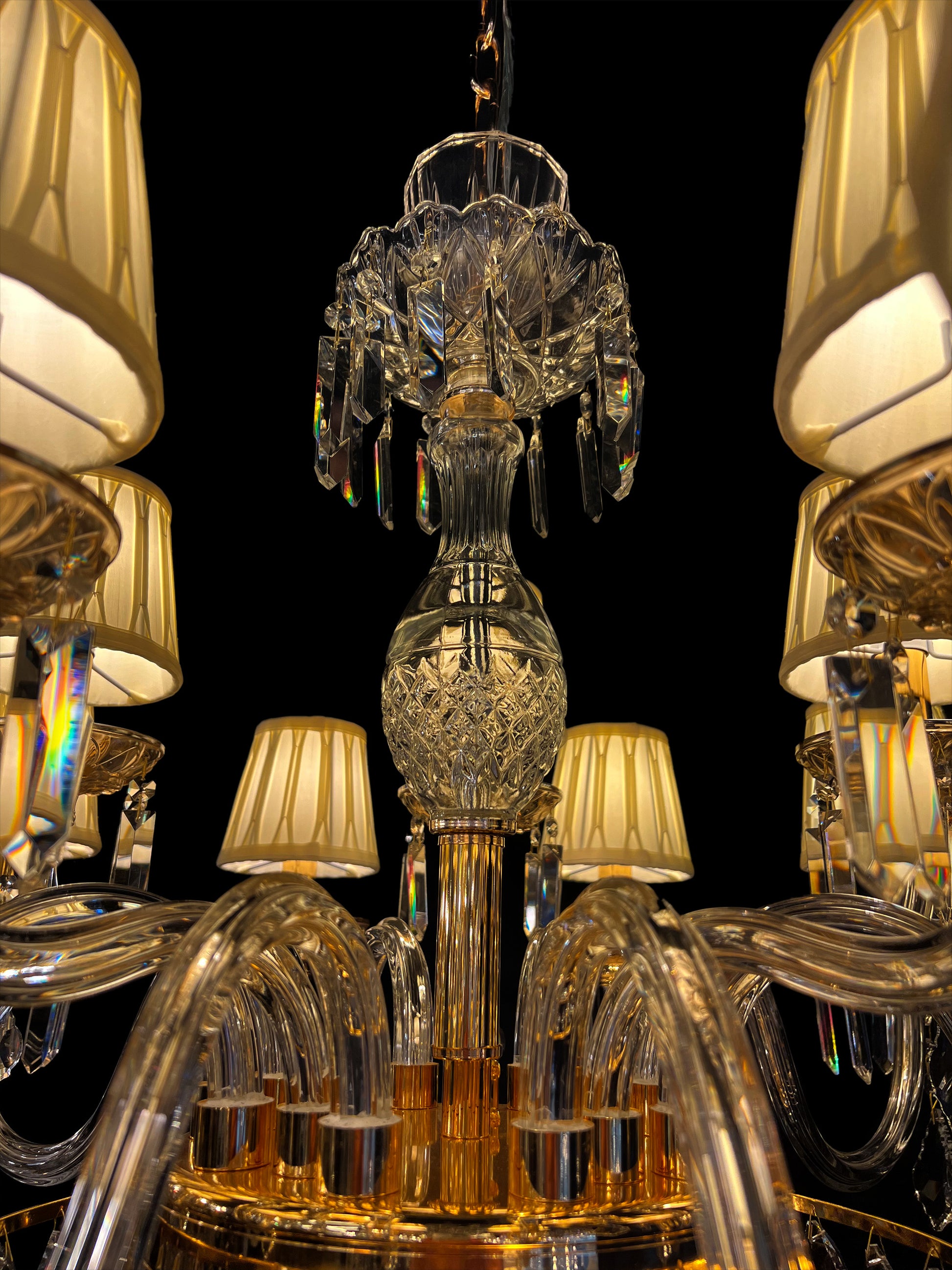 Close-up of luxury gold crystal chandelier showcasing curved crystal arms, faceted crystal ornaments, and elegant gold detailing under warm lighting.