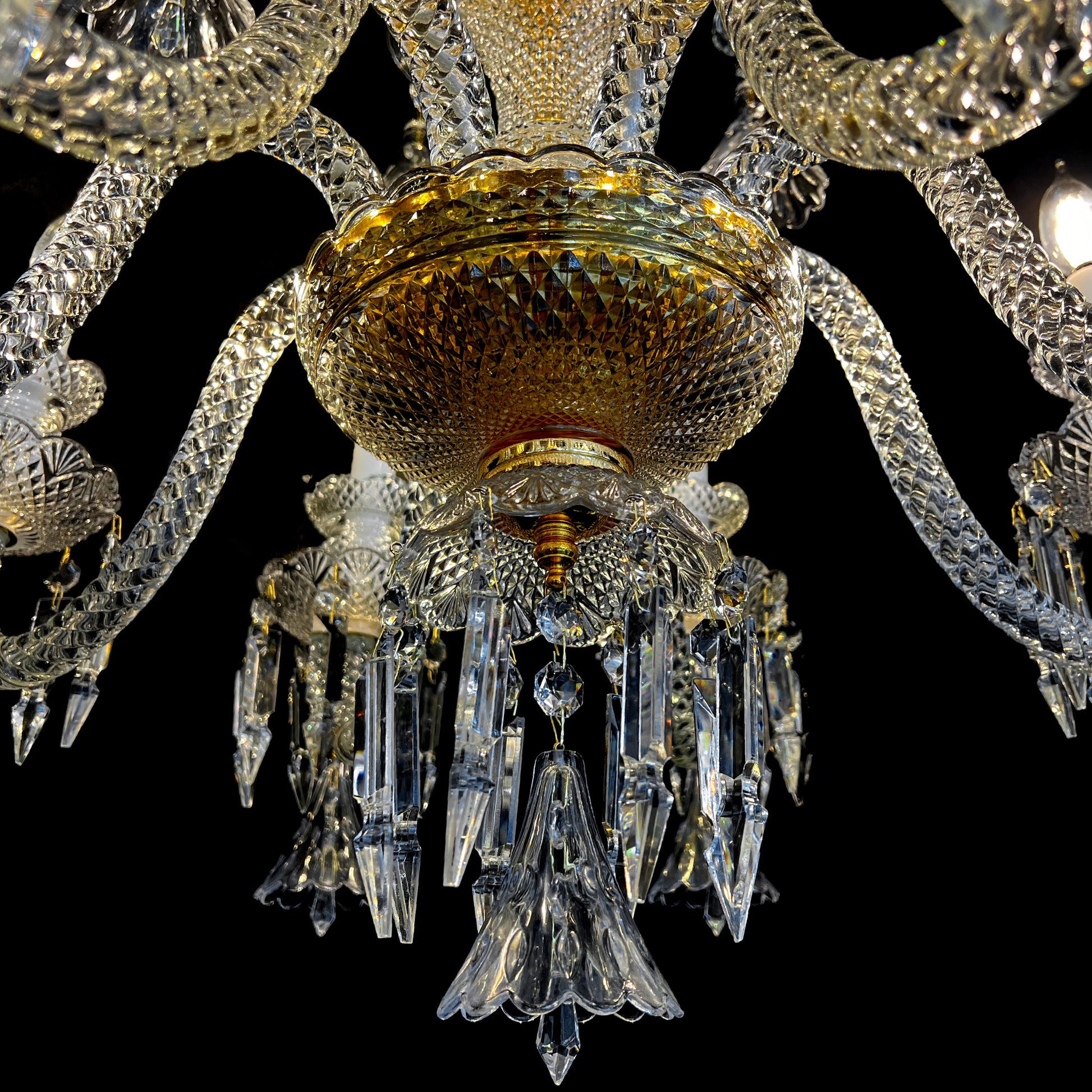 Bottom view of a luxury gold and crystal chandelier showing intricate cut glass details and hanging crystal drops.