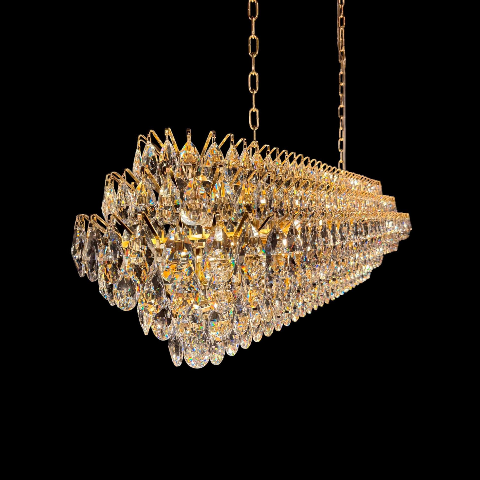 A close-up view of the luxury crystal chandelier's frame, showing precision-cut teardrop crystals securely attached to a polished  gold structure.
