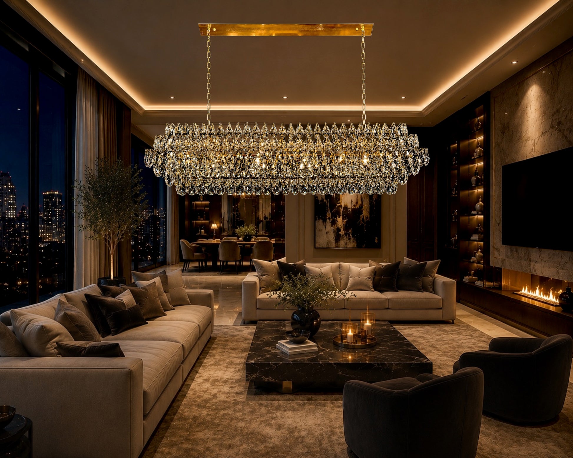 A magnificent linear crystal chandelier with a champagne gold frame lighting up a sophisticated luxury living room, positioned above a modern marble coffee table, plush neutral sofas, and a contemporary fireplace with city night views through large windows.