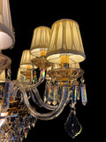 Detailed view of chandelier arm with pleated fabric shade and hanging crystal drops, highlighting the brilliance of gold finish and craftsmanship.