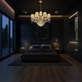 Elegant gold crystal chandelier with fabric shades lighting a modern bedroom with dark walls, wood flooring, and warm ambient glow.