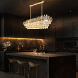 Champagne gold rectangular crystal chandelier with teardrop K9 crystals and a polished linear empire-style design illuminated in warm light.