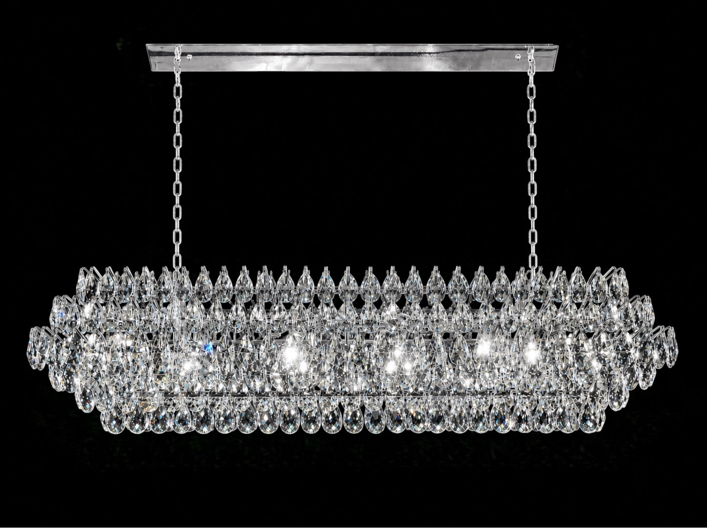 A luxurious 60-inch linear crystal chandelier featuring a polished chrome frame and multiple tiers of precision-cut teardrop crystals, shown hanging from a rectangular canopy with dual chains against a solid black background.