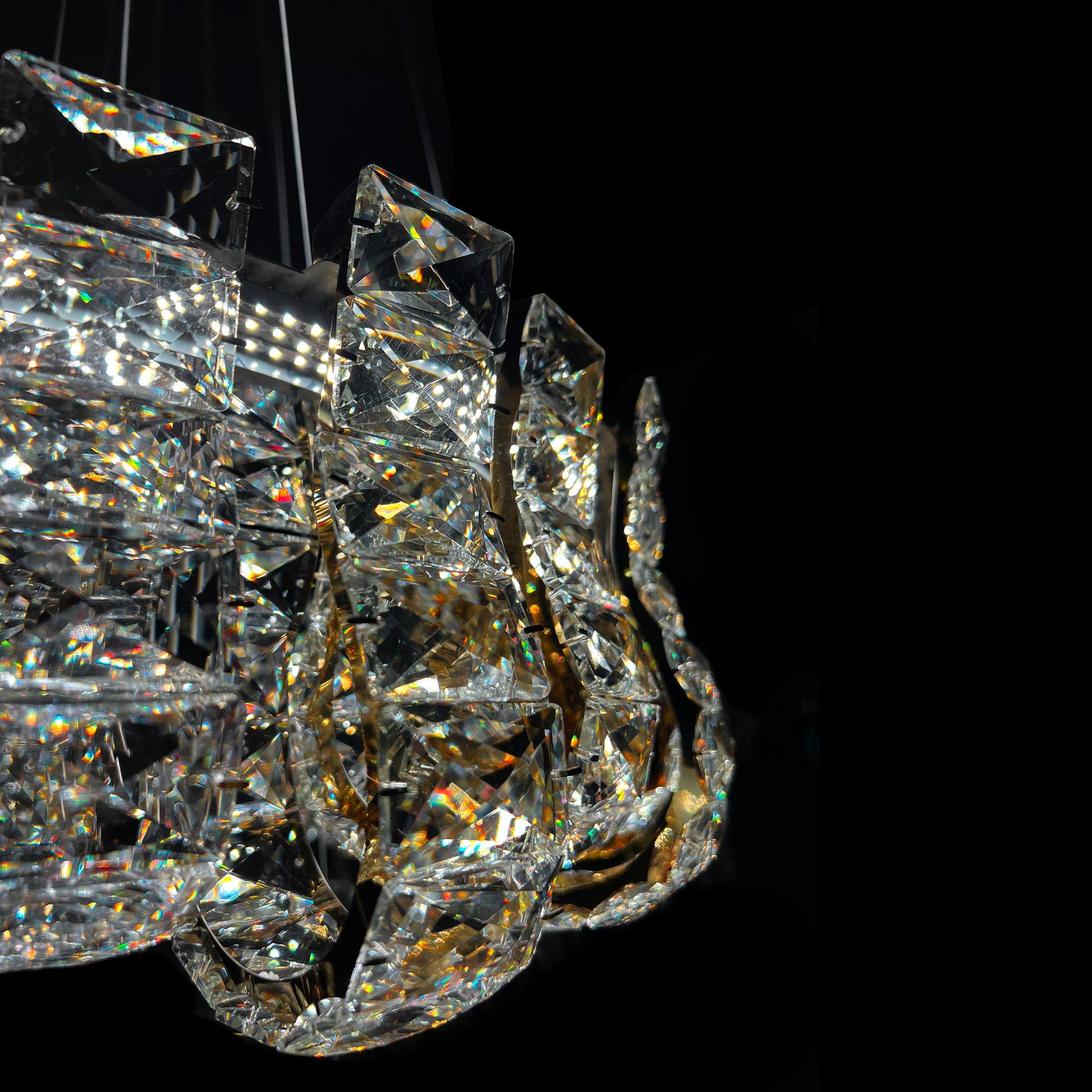 Closeup of luxury K9 crystal chandelier showing intricate gold frame and reflective crystal details.
