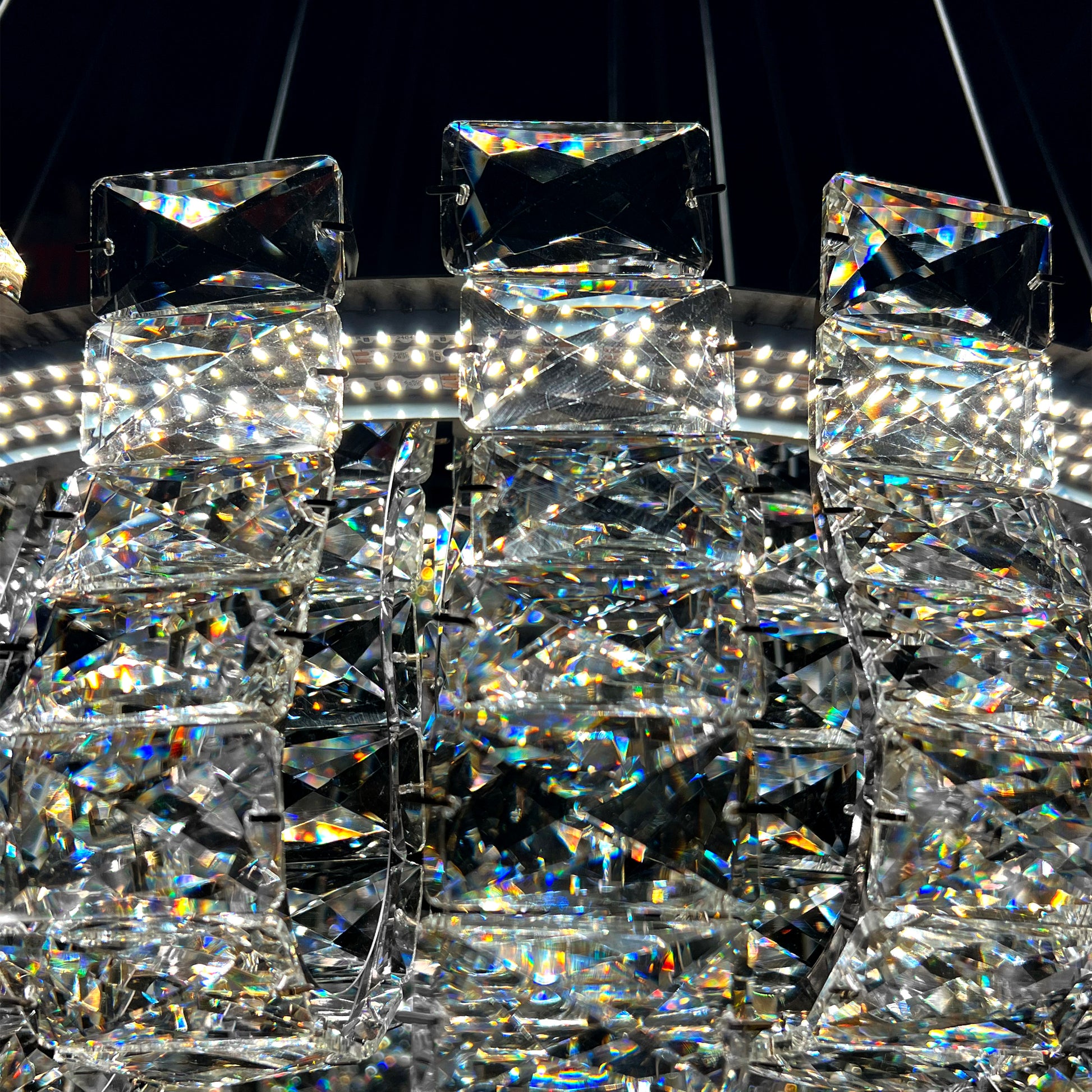 Closeup of luxury K9 crystal chandelier showing intricate silver frame and reflective crystal details.
