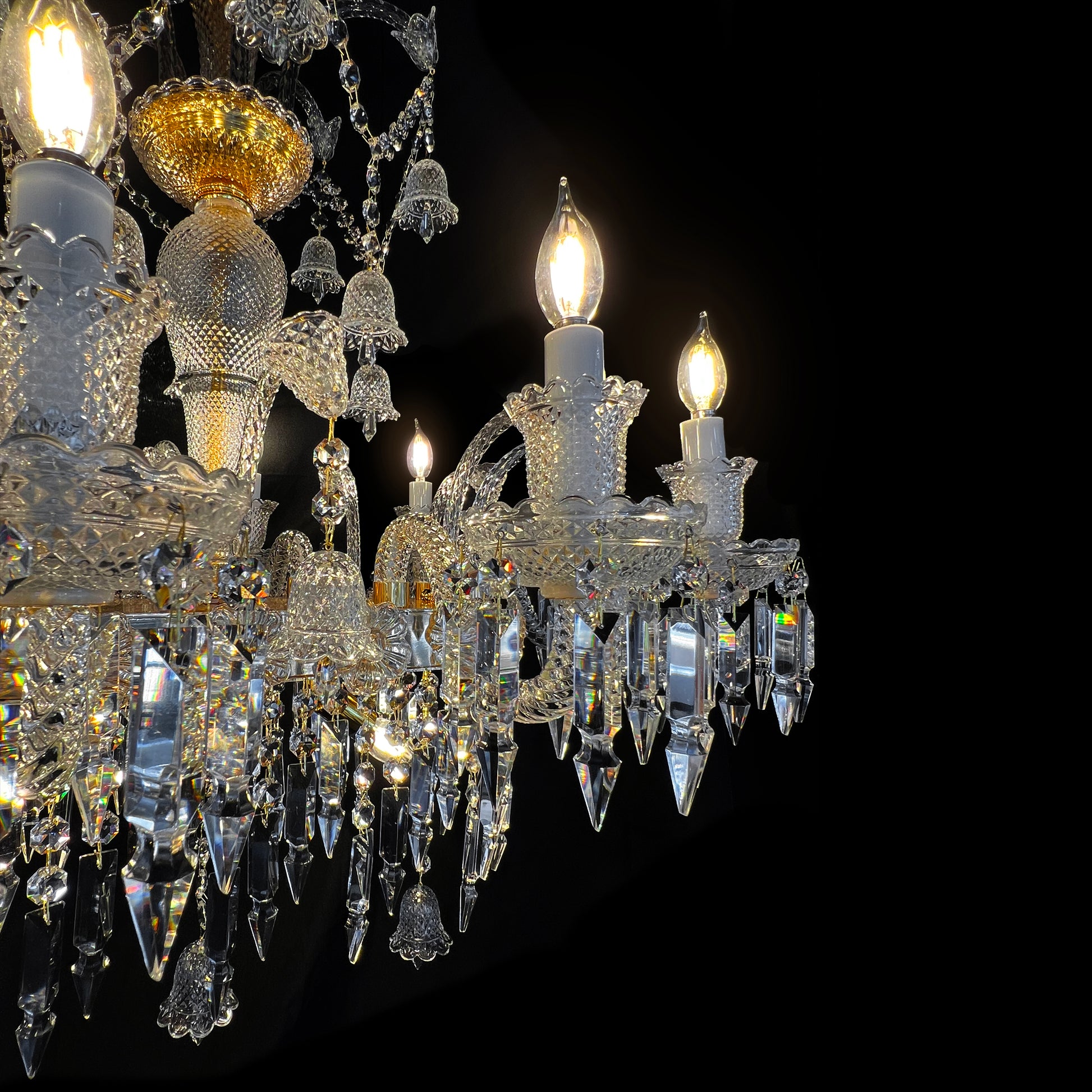 Detailed view of glass crystal drops and gold plated base of luxury Baccarat style chandelier with artisanal craftsmanship.

