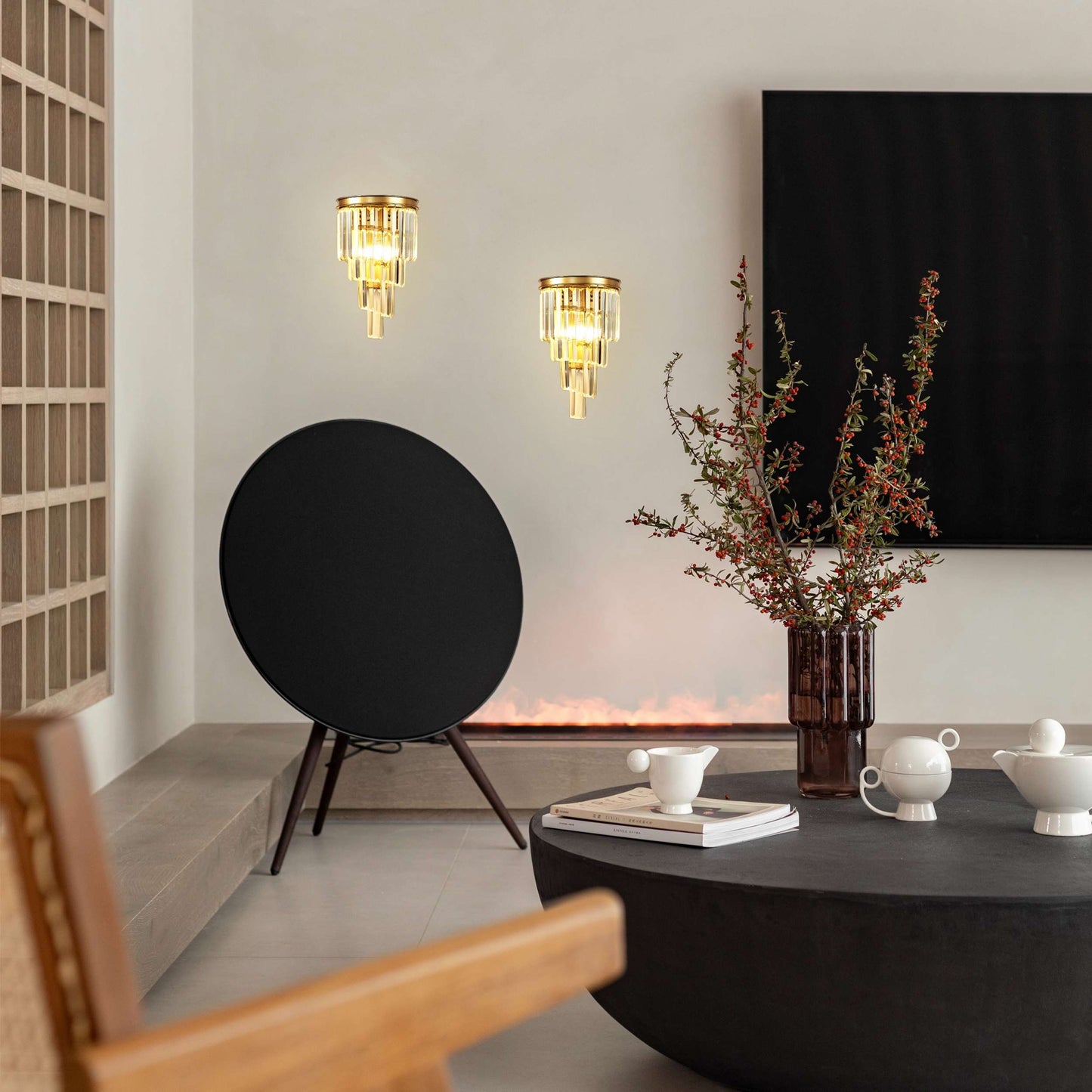 Modern living room with black round speaker, wall lights, and decorative items.