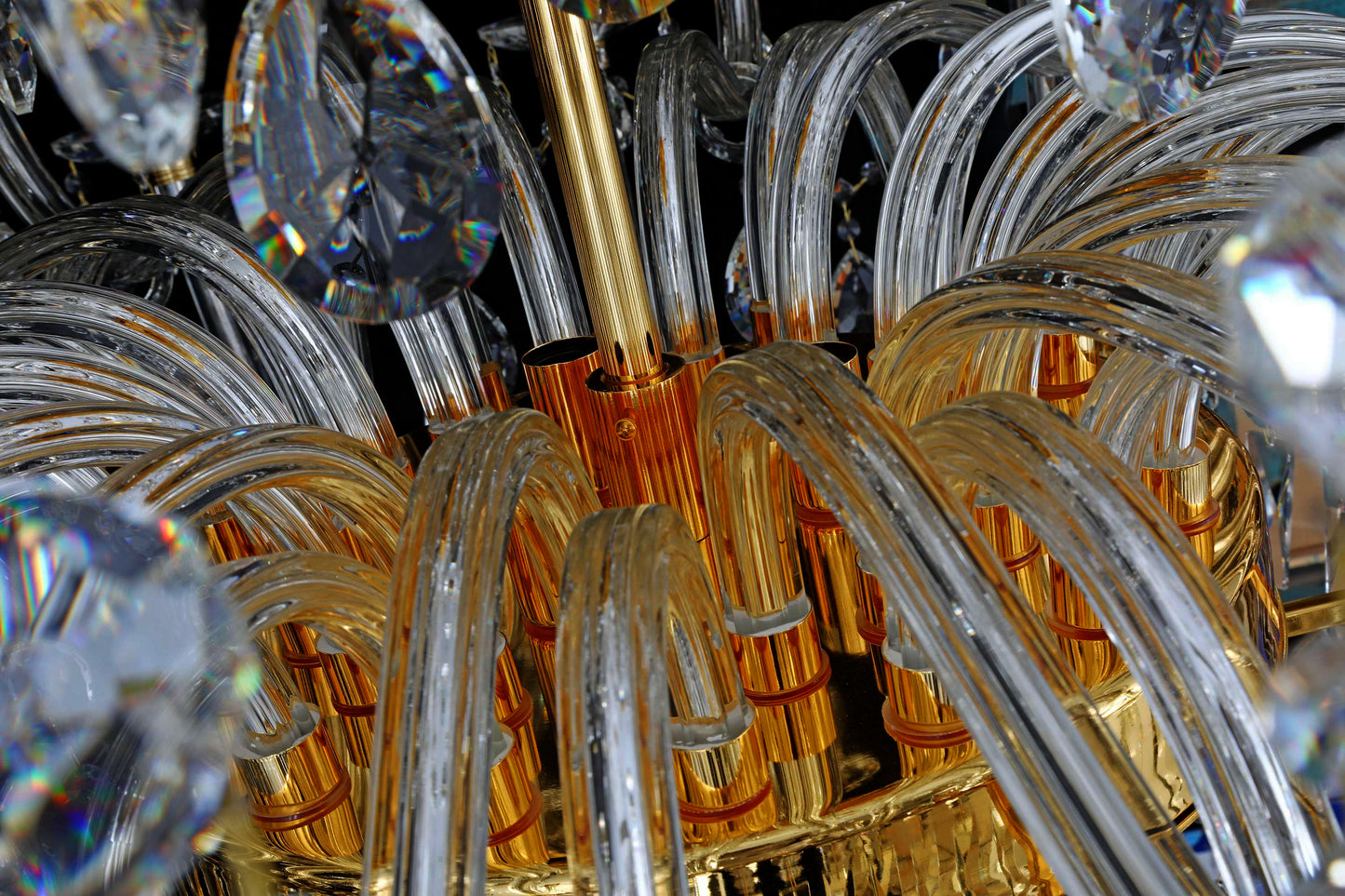 Detailed view of curved crystal clear arms and gold fittings of the empire chandelier.