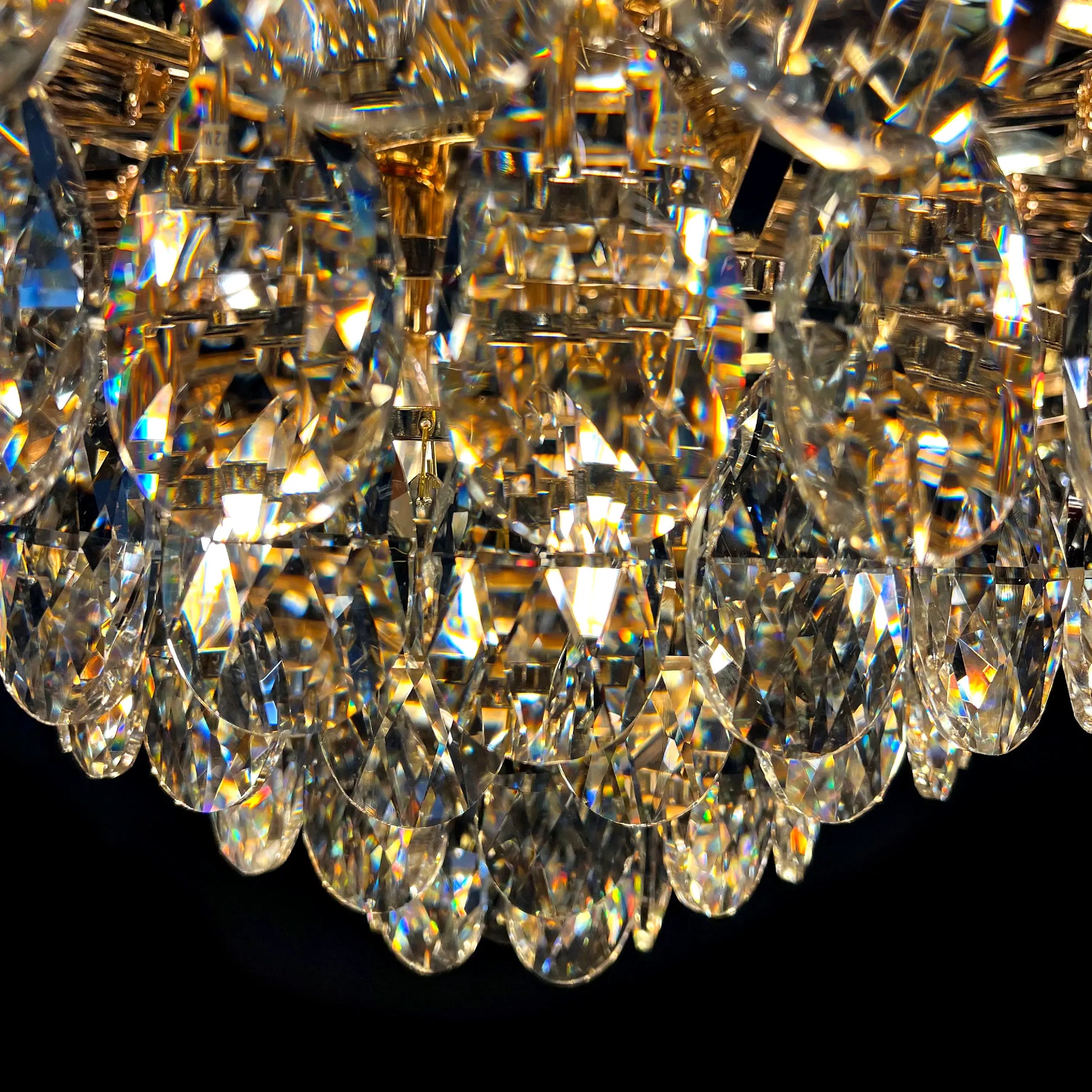 Detailed close-up of gold crystal chandelier with reflective luxury tear drop crystals.
