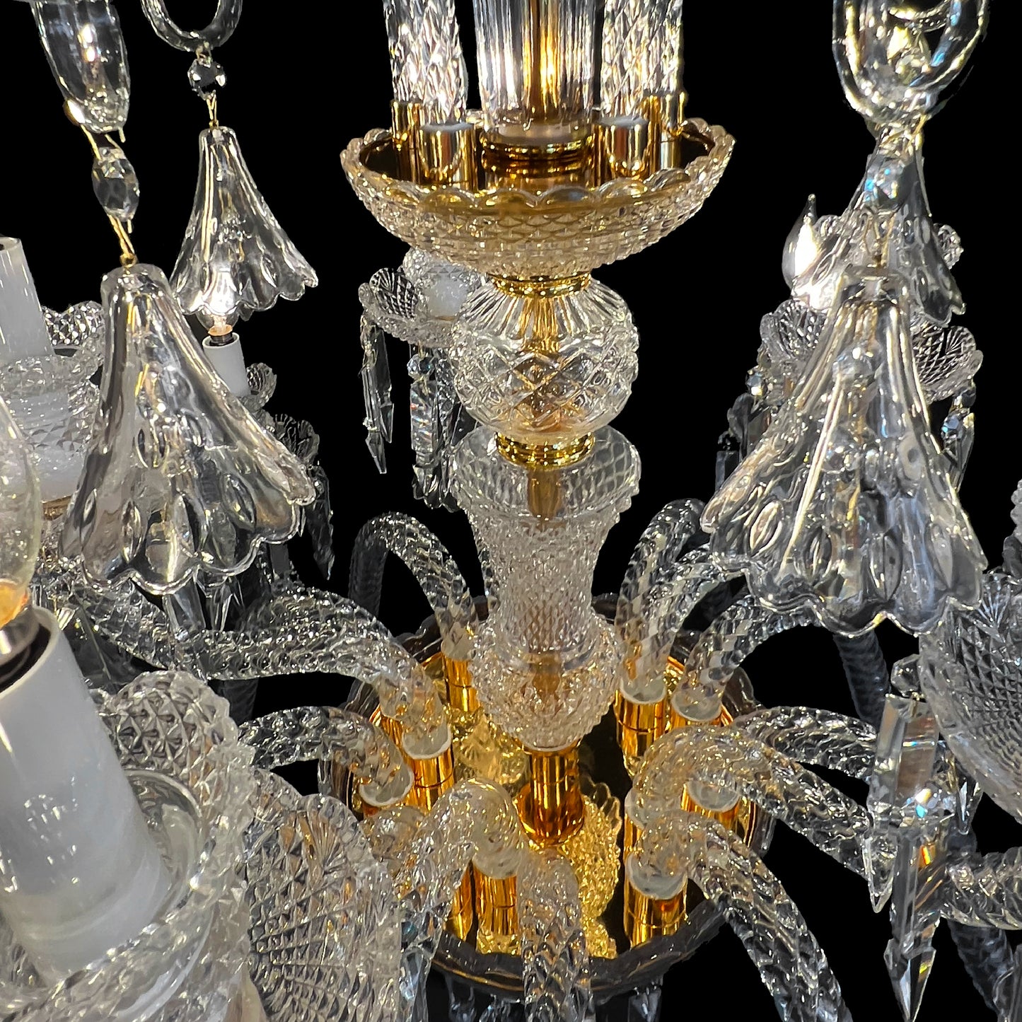 Close up view of a luxury gold and crystal chandelier showing intricate glass arms and gold accents.