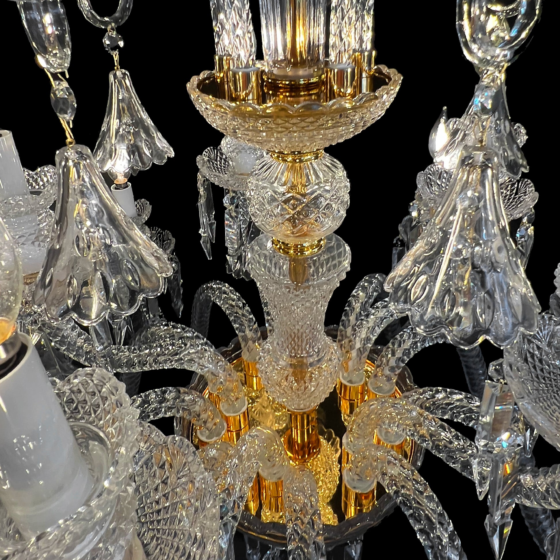 Close up view of a luxury gold and crystal chandelier showing intricate glass arms and gold accents.