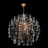 A gold-finished metal frame chandelier with cascading crystal droplets and illuminated by halogen bulbs.