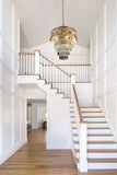 Modern gold tiered crystal chandelier illuminating staircase interior