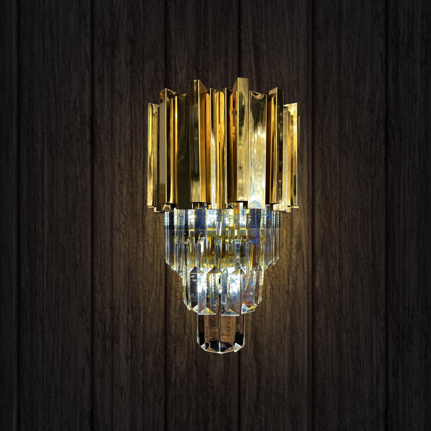 gold tiered crystal LED wall sconce on dark wall