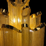Detailed macro shot highlighting the stainless steel frame and reflective gold chains of the chandelier’s upper tier.

