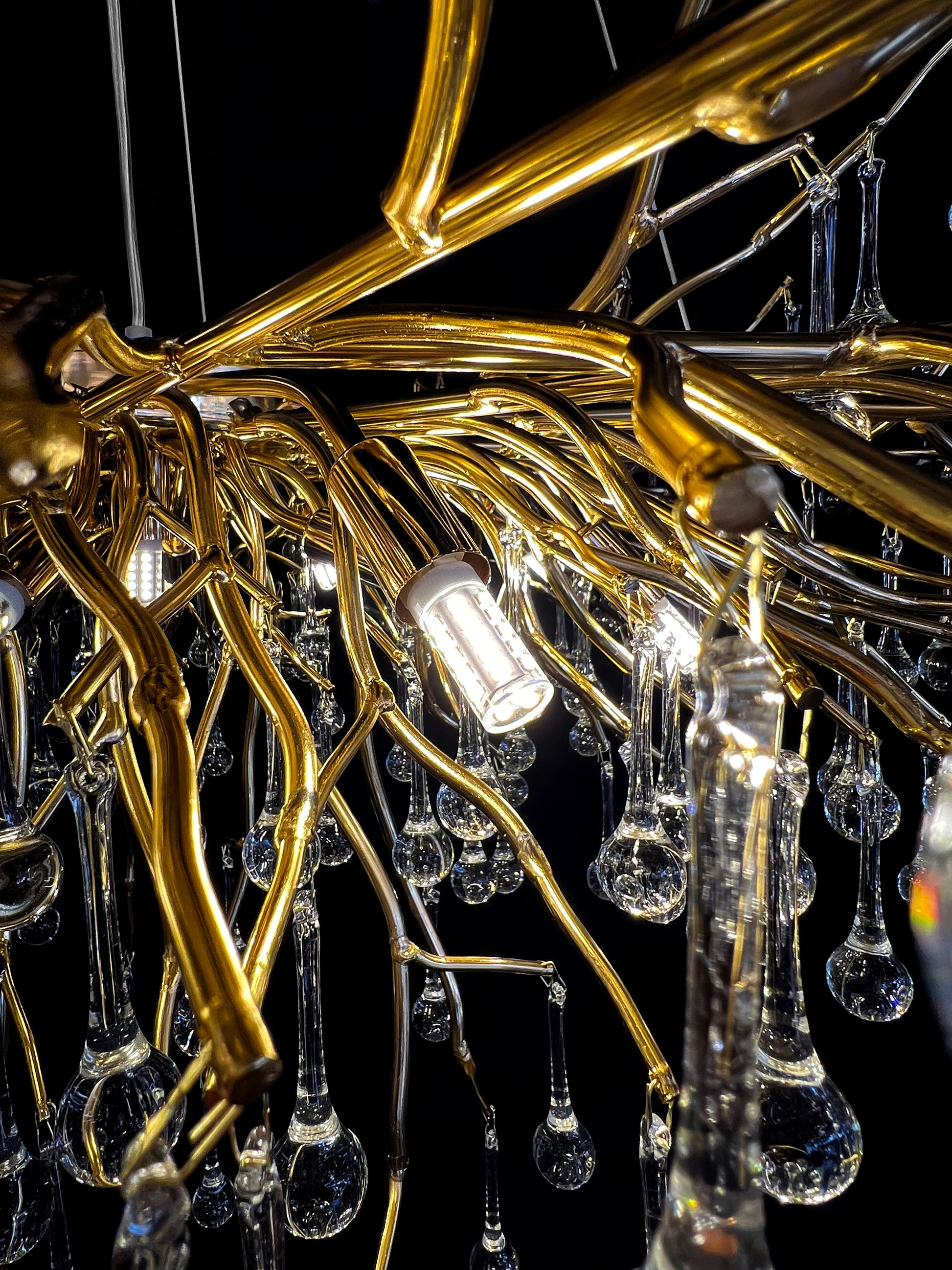 Side angle of gold branch chandelier showing glass reflections with G9 LED bulbs