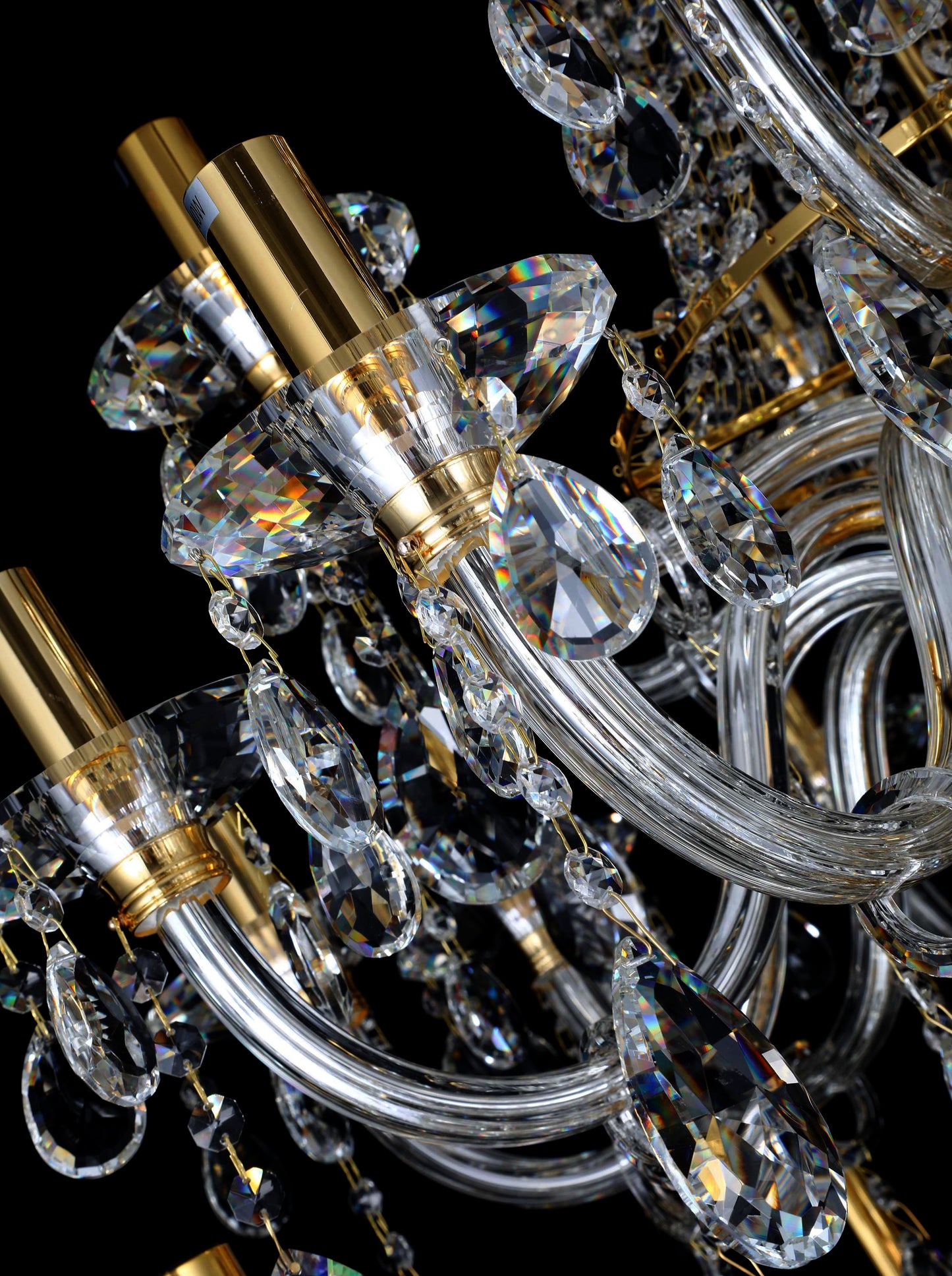 Upper section of chandelier featuring curved gold arms and tear drop crystal 