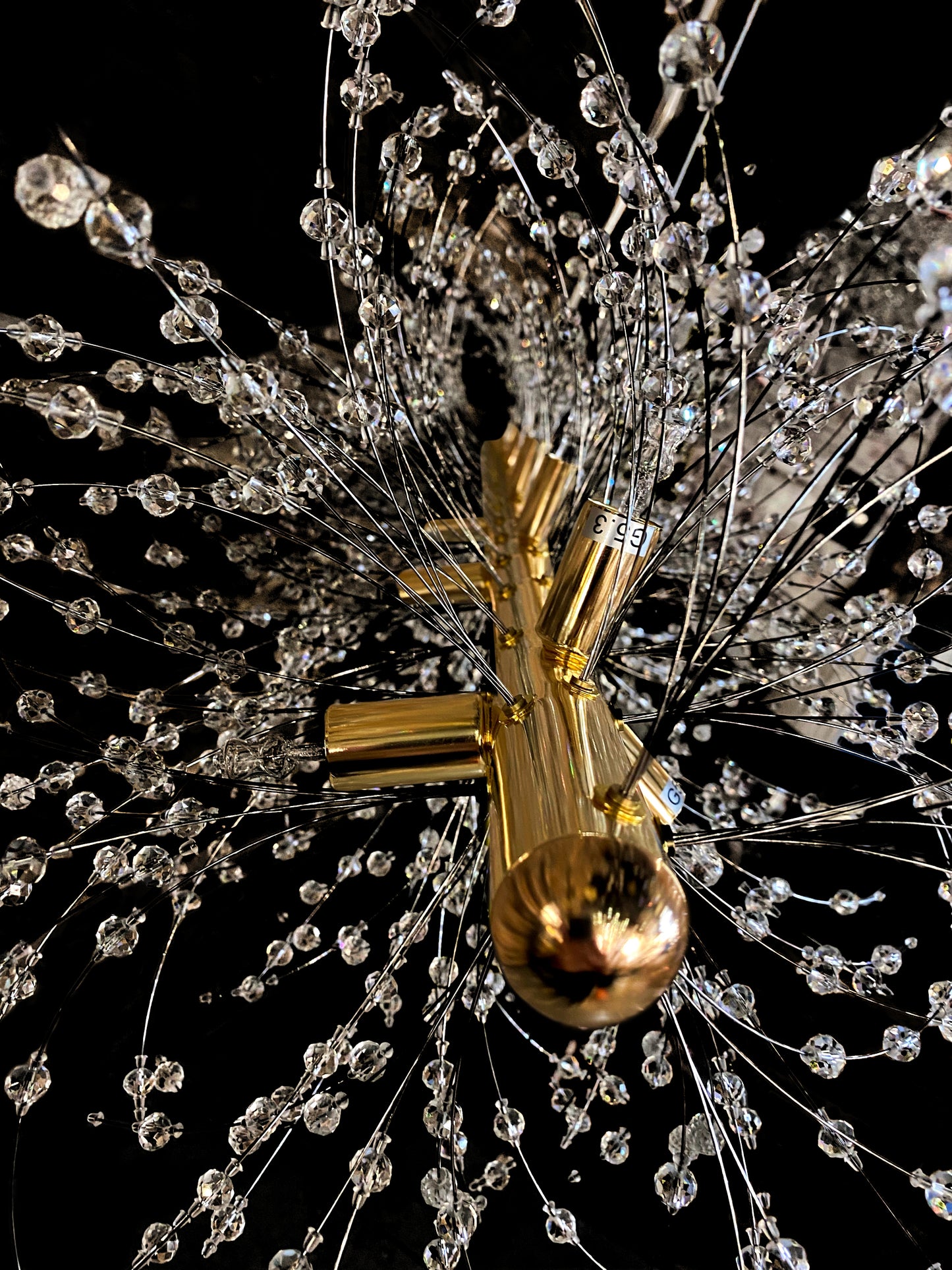 Precision-cut crystal branches detail on modern gold chandelier