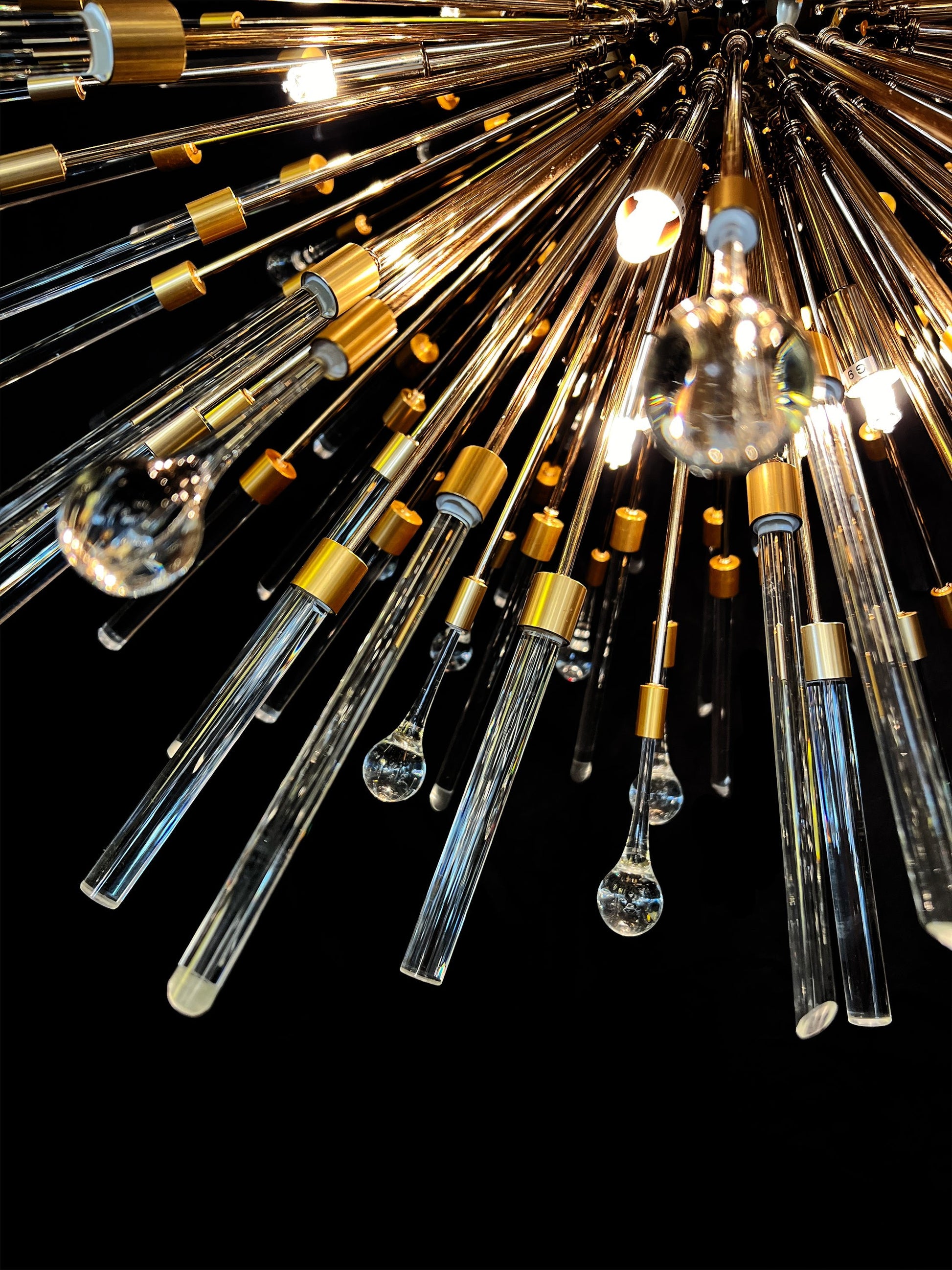 Modern pendant chandelier with gold frame and luminous glass rods.