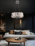 chrome dimmable crystal LED chandelier illuminating a luxury living room with modern décor and dark walls.
