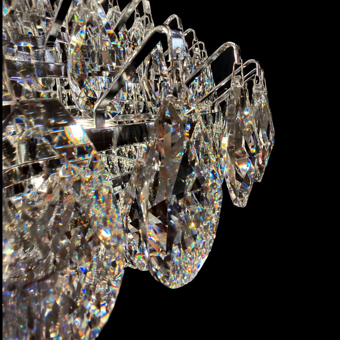 Detailed close-up of a luxury diamond-teardrop shaped crystal chandelier showing the sparkling multi-tiered crystals and chrome frame.