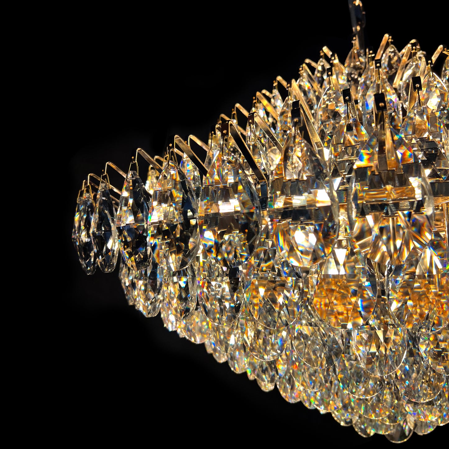 Detailed close-up of a luxury diamond-shaped crystal chandelier showing the sparkling multi-tiered crystals and gold frame.