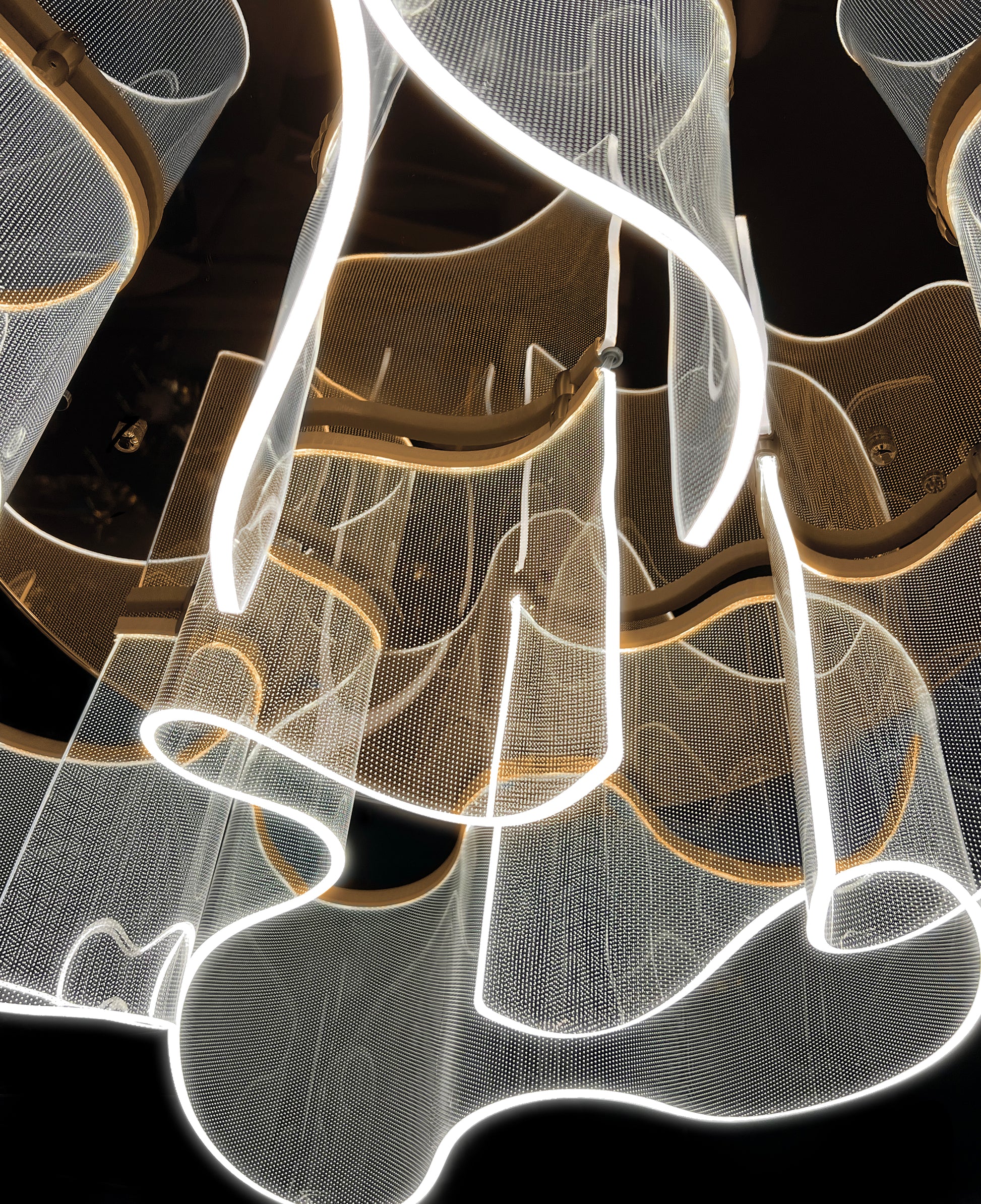 : Close-up of gold acrylic LED chandelier with soft illuminated curves