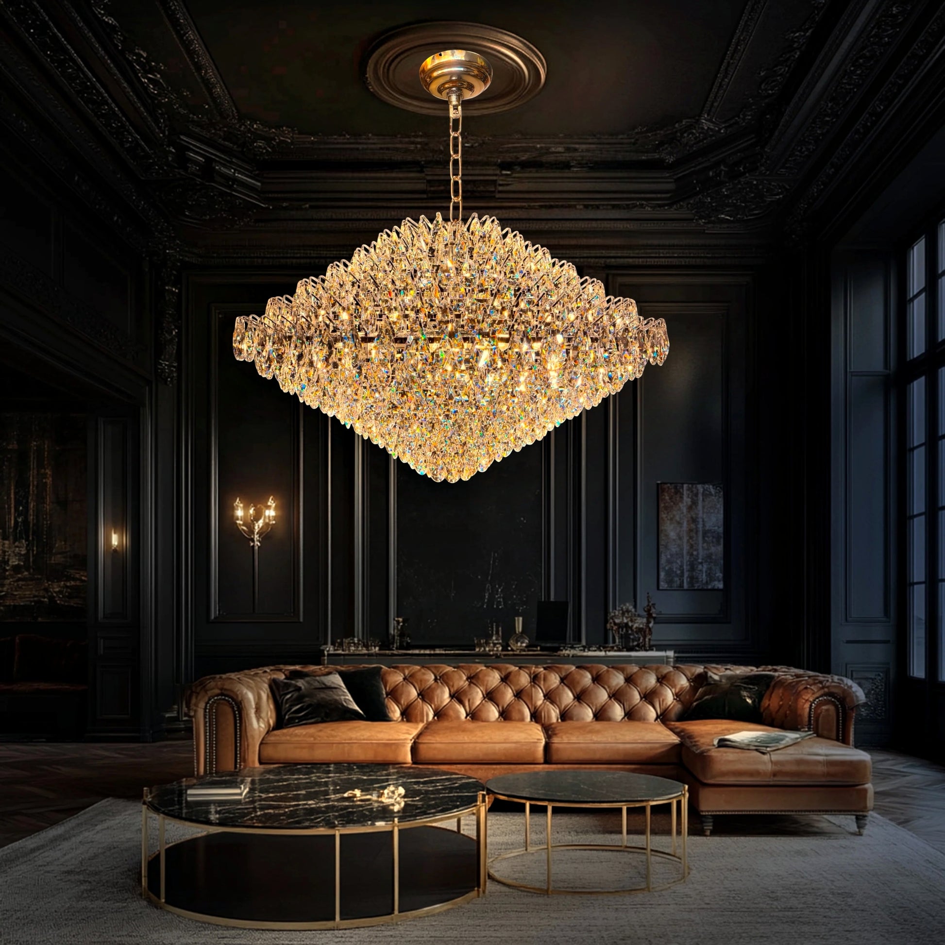 A luxurious diamond-shaped crystal chandelier hanging in a dark modern living room with a brown leather sofa.