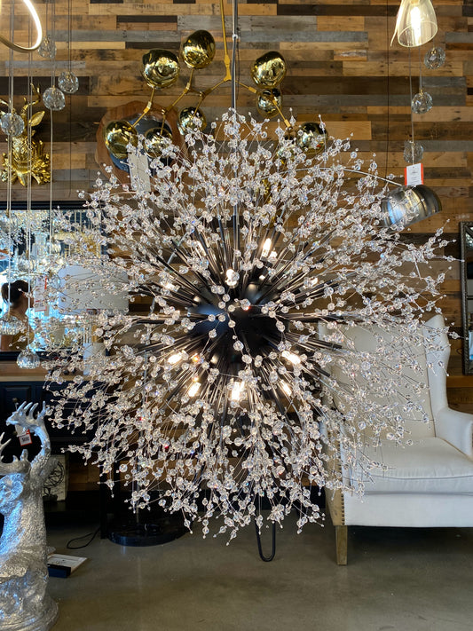 A luxurious black crystal chandelier with a starburst design, featuring matte black tubes and crystal beads, displayed in a showroom setting.