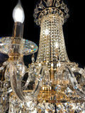 Upper section of chandelier featuring curved gold arms and crystal chains.”