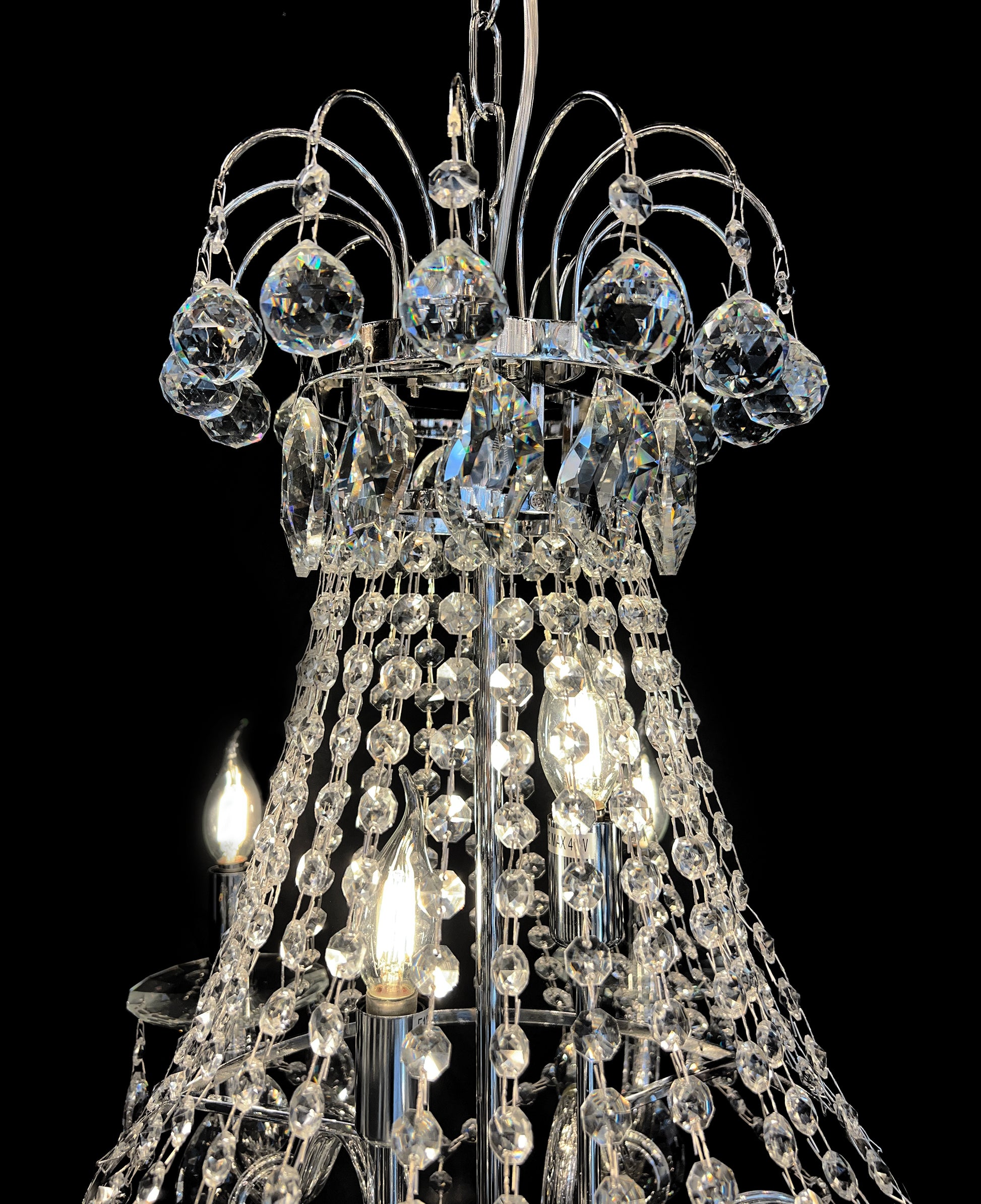 Upper section of chandelier featuring curved chrome and different size  crystal design 