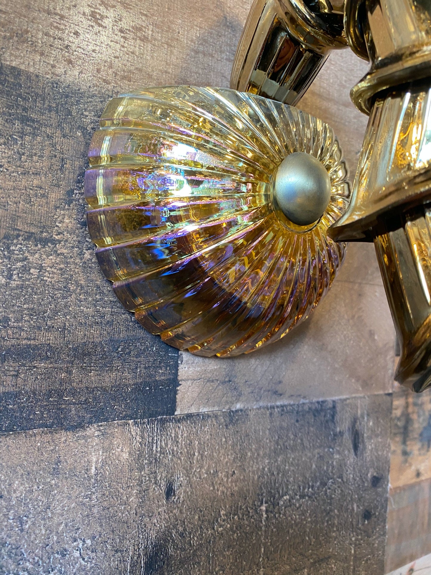 Decorative wall sconce with gold and glass design on a textured wall.
