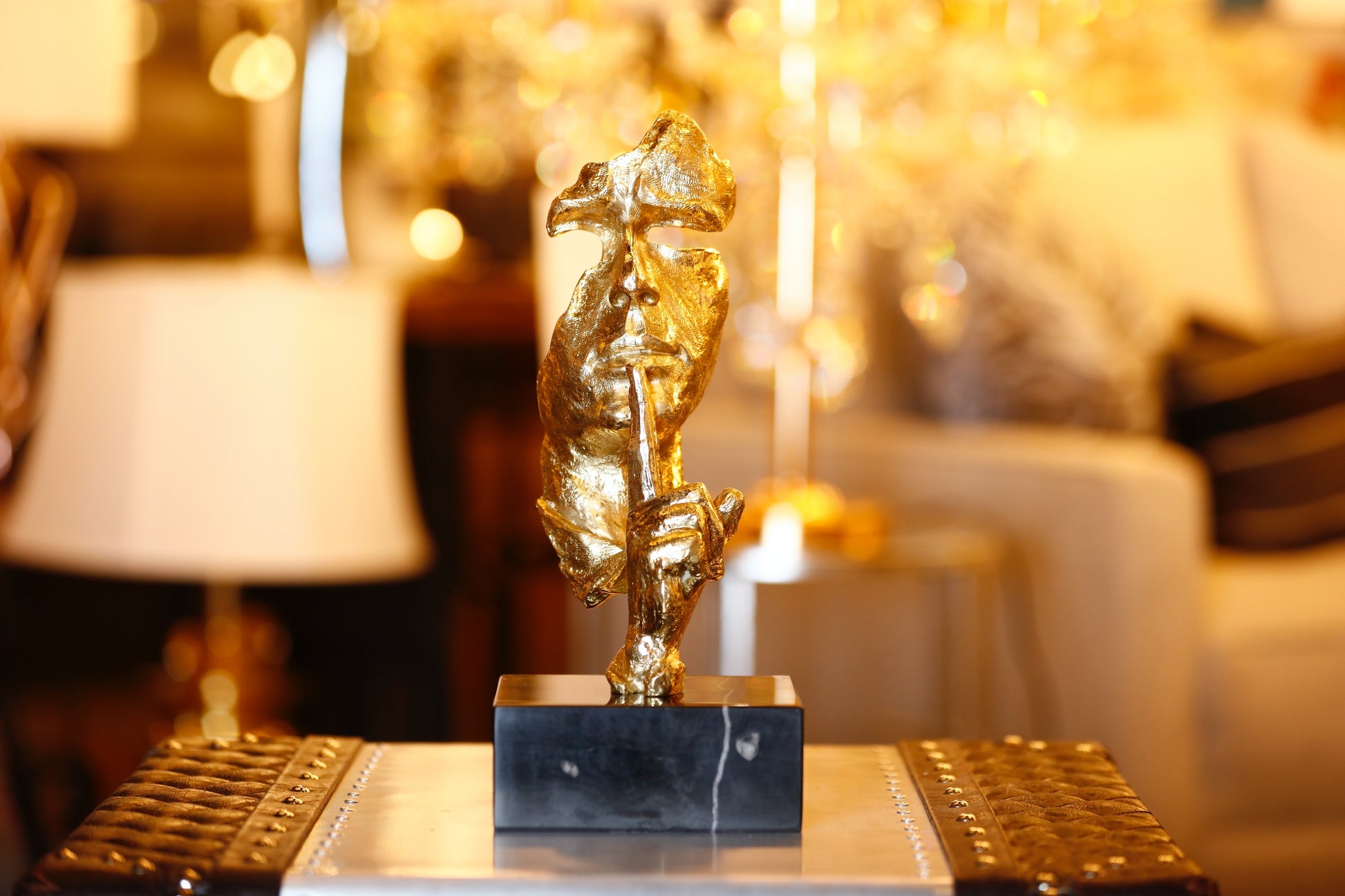 Modern handcrafted Italian solid brass Silence sculpture on a black marble base with a gold lacquer finish.