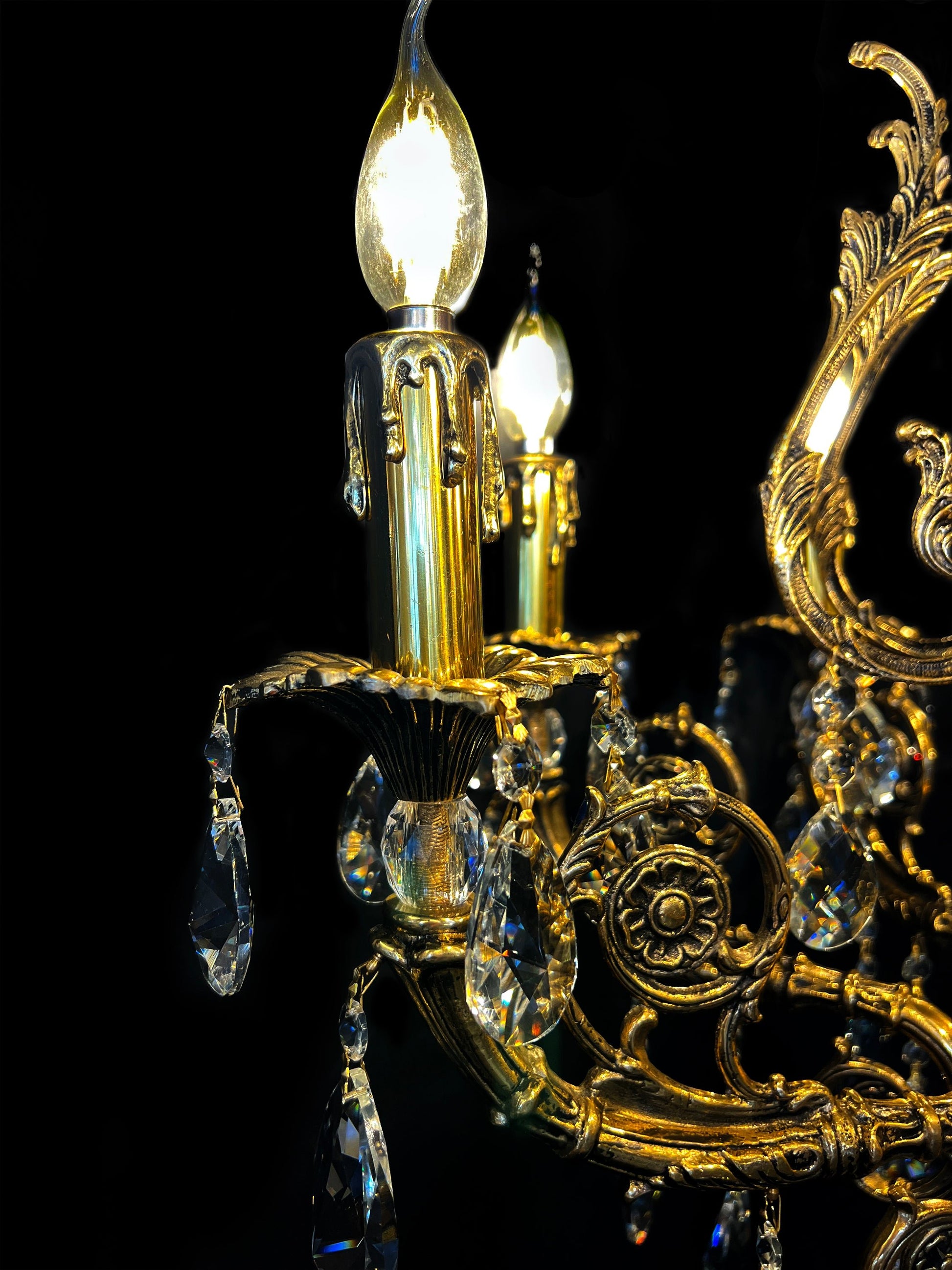 Close-up of handcrafted Italian brass chandelier arm with crystal drops and candle light