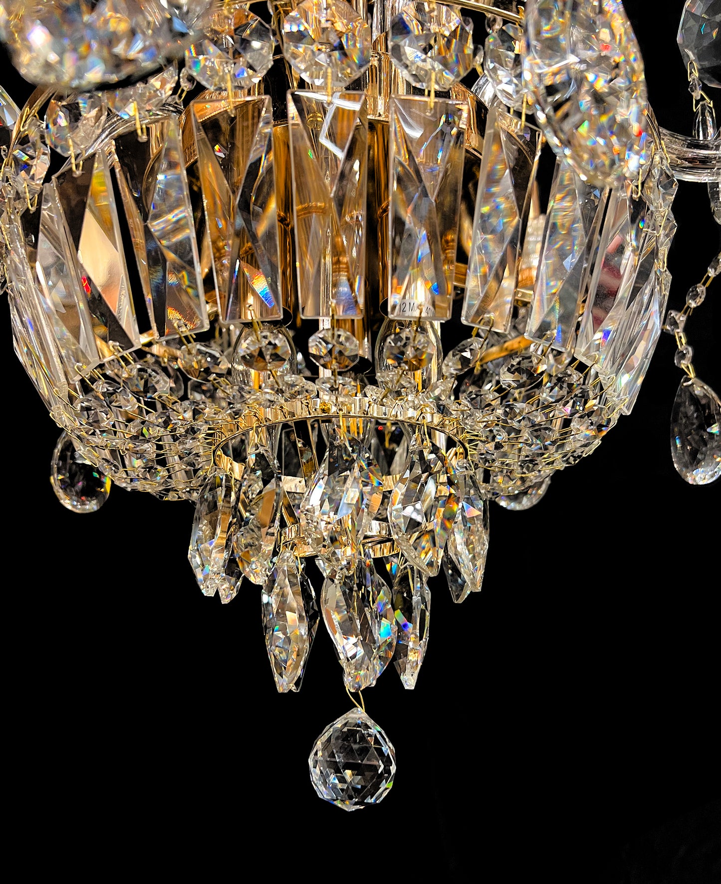 Detailed gold chandelier base with hanging crystals reflecting warm light