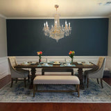 Elegant gold crystal chandelier above classic dining table with modern wall paneling