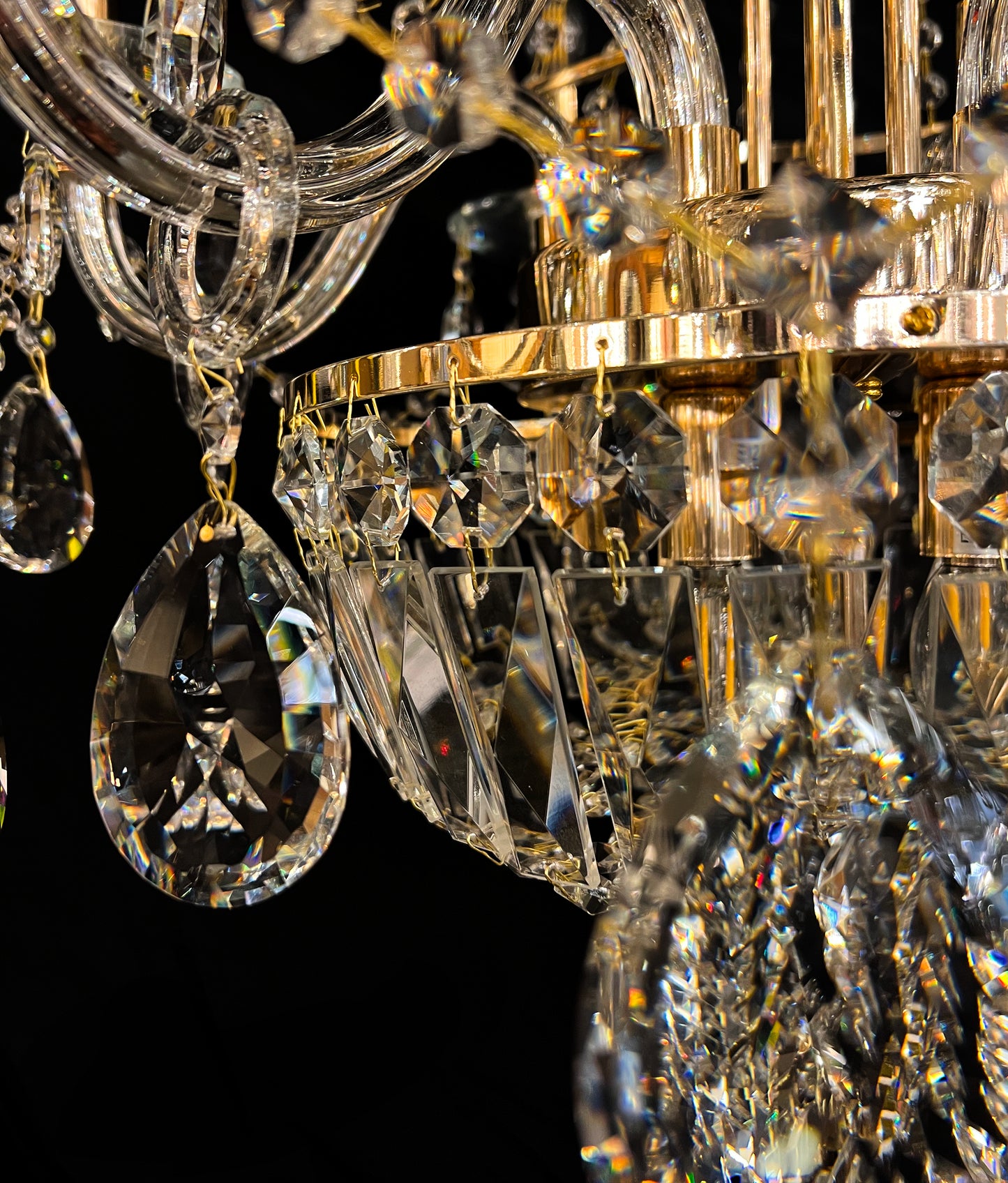 Detailed gold chandelier base with hanging crystals reflecting warm light.”